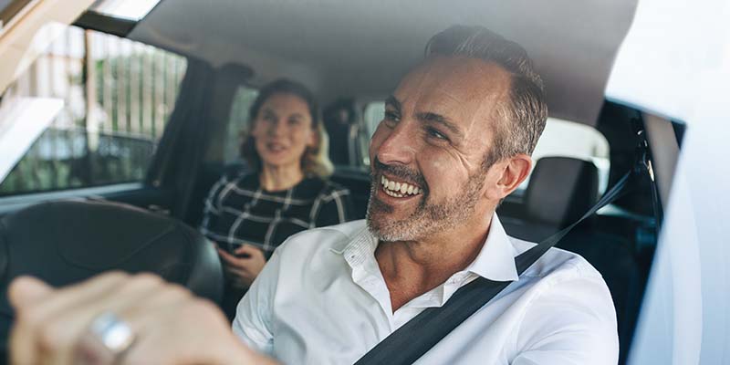 Taxi driver talking to a female passenger sitting in backseat. Businesswoman using taxi ride to go to work.